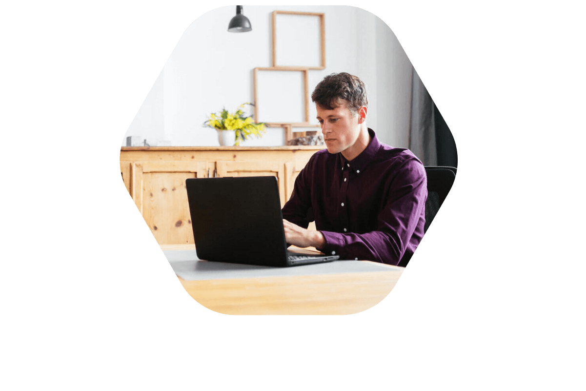 A man working at a desk with a laptop, illustrating the use of Bullhorn Workforce Management software in a staffing agency context.