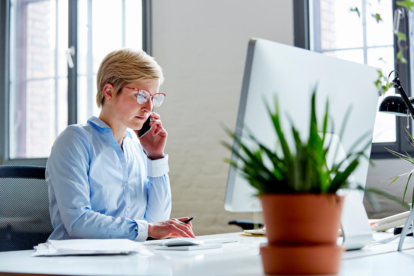 Footer Businesswoman Using Mobile Phone At Desk In Office