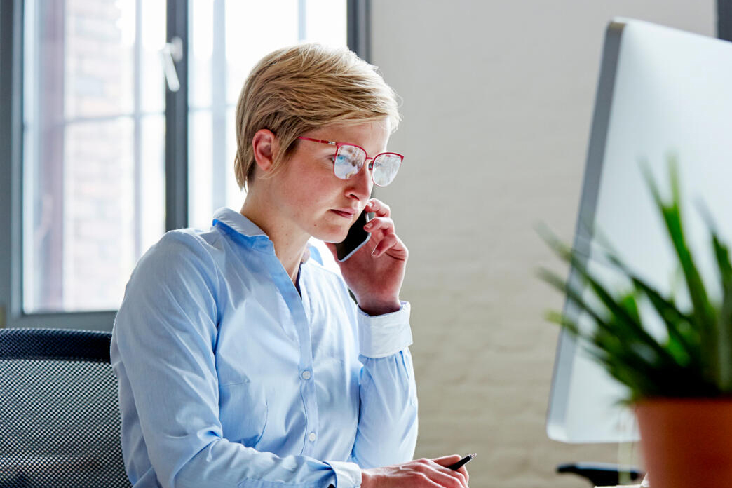 Businesswoman Using Mobile Phone At Desk In Office